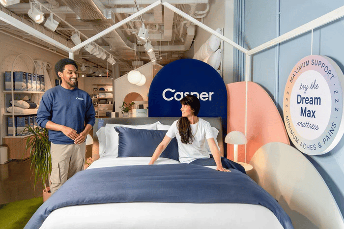 Two people examining a Casper mattress in a store setting.