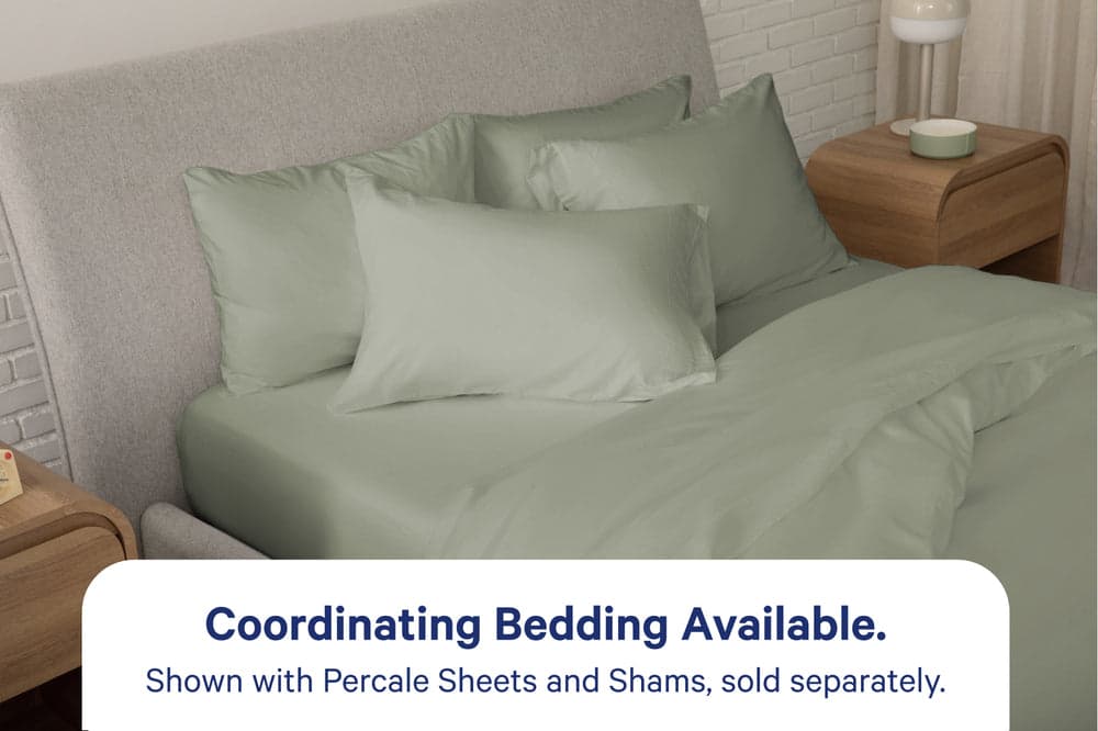 A fully dressed bed with eucalyptus-green bedding. An overlay on the image with text reads 'Coordinating Bedding Available. Shown with Percale Sheets and Shams, sold separately.'