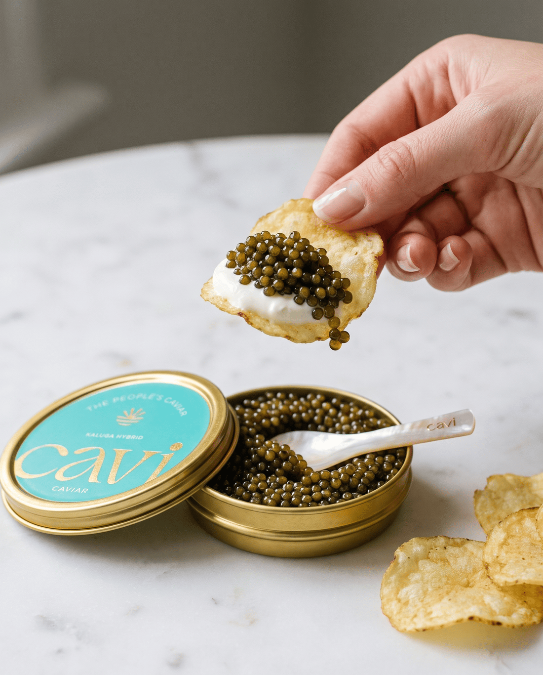 Caviar and creme fraiche on a kettle chip with an open CAVI tin