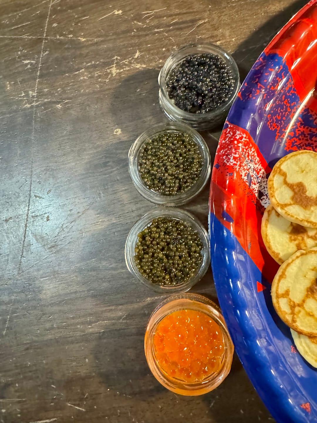 Customer's CAVI Beginner Tasting Kit showing four small glass tins of varied caviar next to small pancakes.
