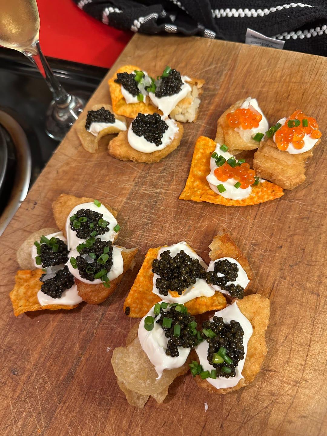 Reviewer's Siberian Sturgeon Caviar dollops on chips with cream and chives on a wooden board.