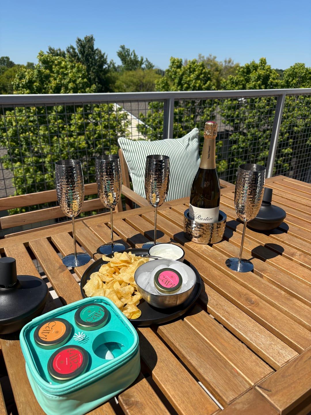 Customer's patio table set with CAVI caviar tins, sparkling wine, and chips for a celebration.