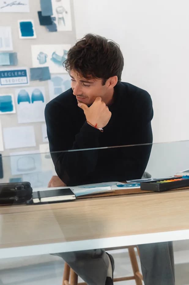 Charles Leclerc at a desk, looking at a laptop