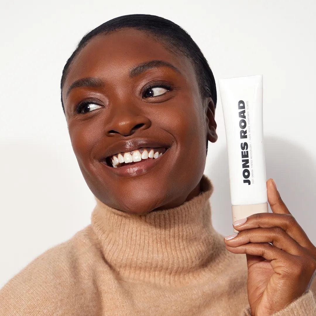 Model applying Just Enough Tinted Moisturizer