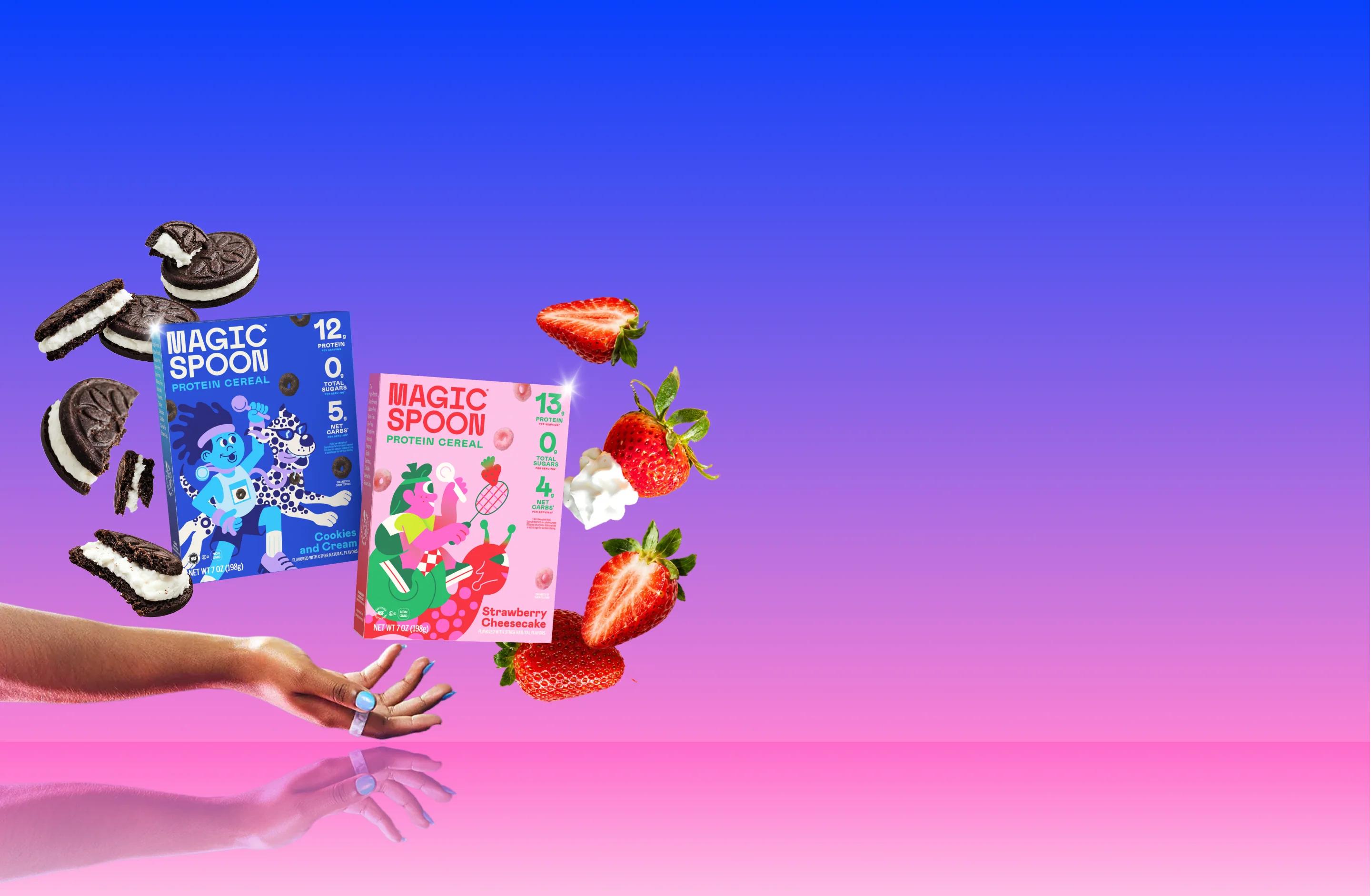 Cookies & Cream and Strawberry Cheesecake cereal boxes floating above an open hand, surrounded by sandwich cookies and strawberries