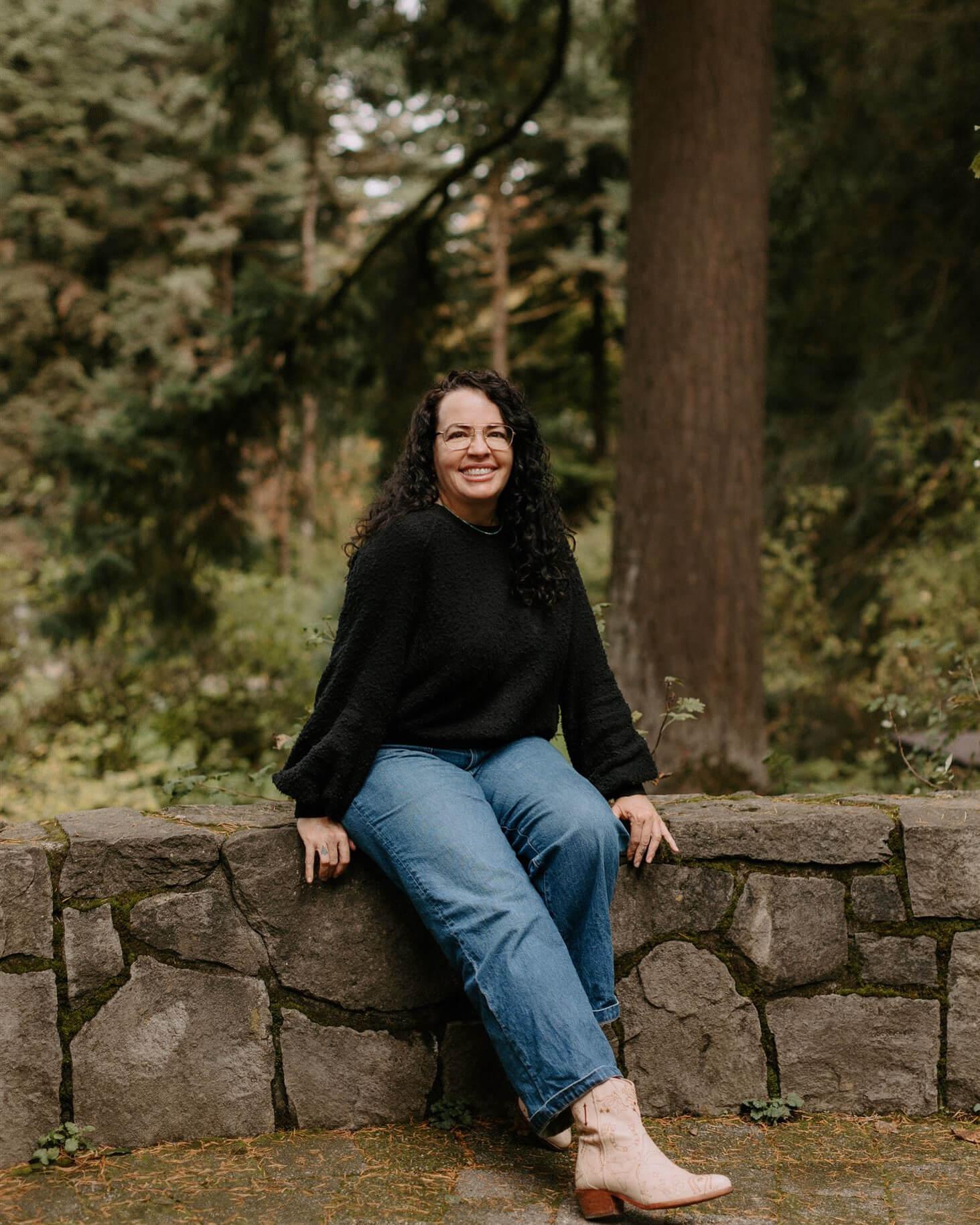 Photo of Ellishea Leal of E Aesthetics and Acne Care sitting outdoors on a low stone fence