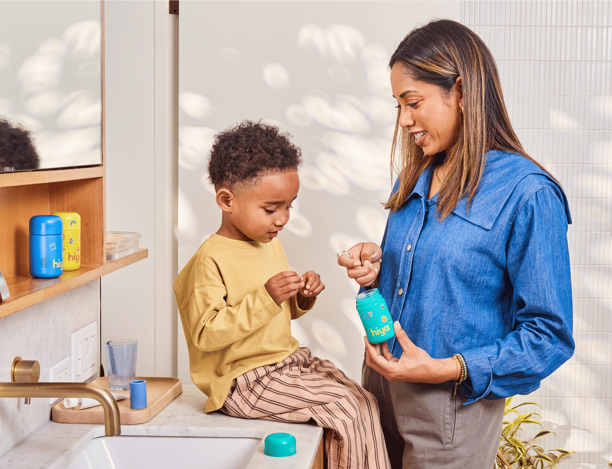 Woman and child in a bathroom setting with a blue Hiya bottle