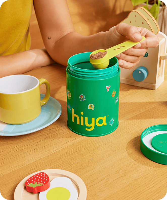 Child scooping a Hiya vitamin from the bottle