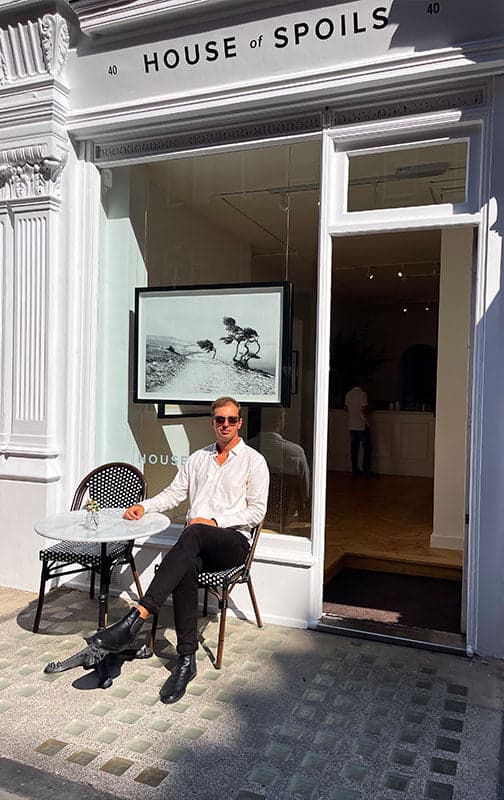 House of Spoils storefront with a visitor seated outside
