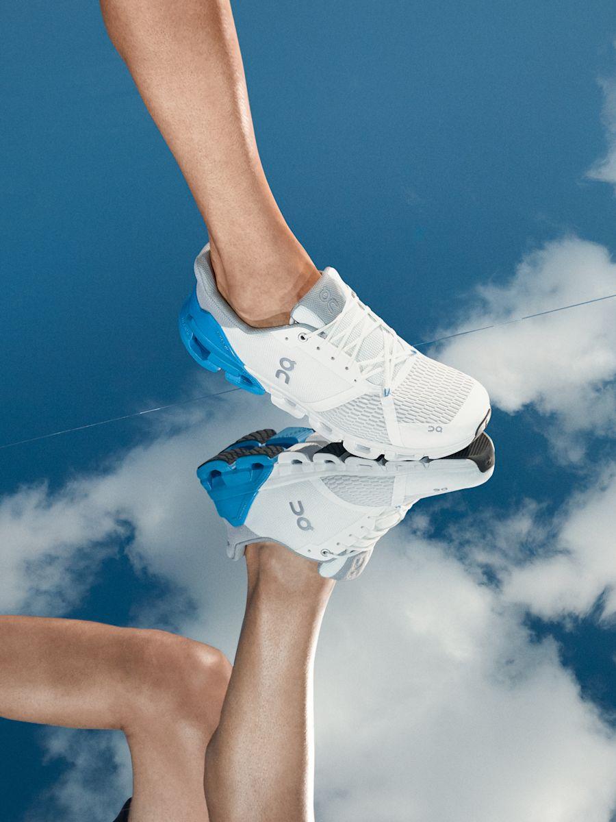 Person wearing blue and white Cloudflyer stepping onto a mirrored surface with clouds.