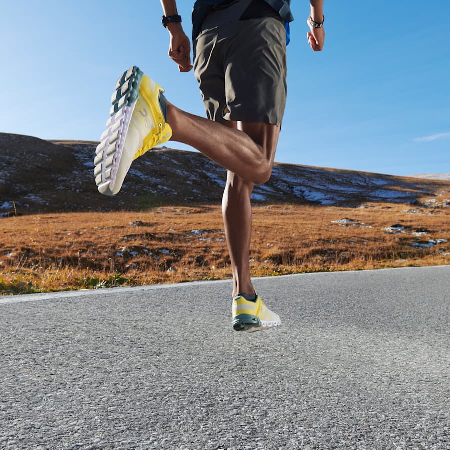 Runner mid-stride wearing On shoes on a road with mountains