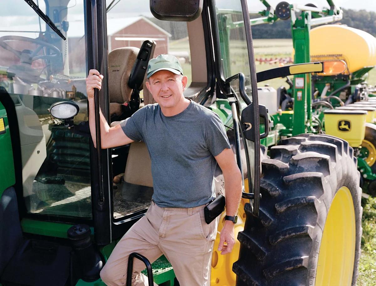 Farmer standing beside a green tractor in a field at Turek Farms