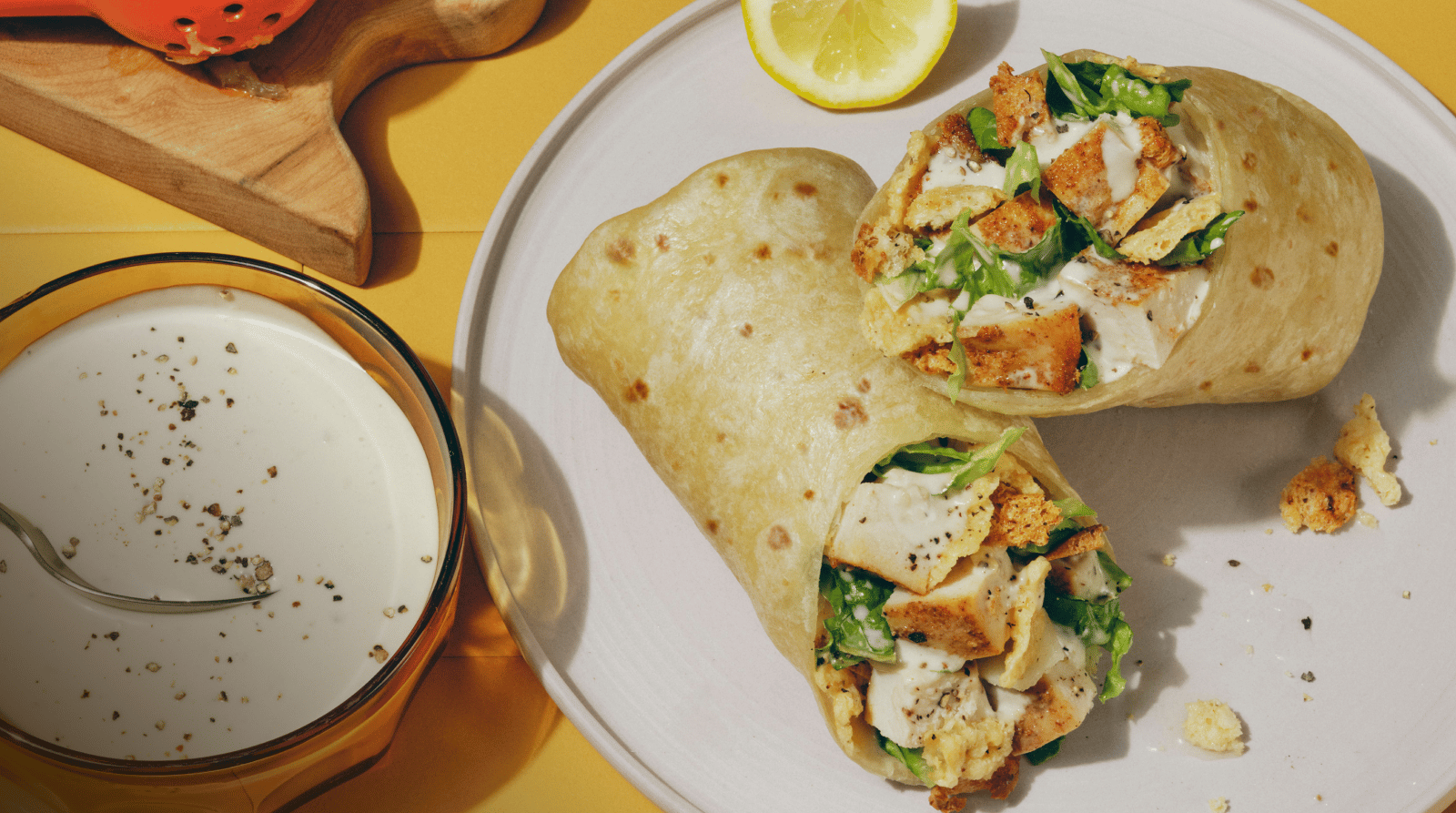 Classic Chicken Caesar wrap on a plate with a yellow tile background