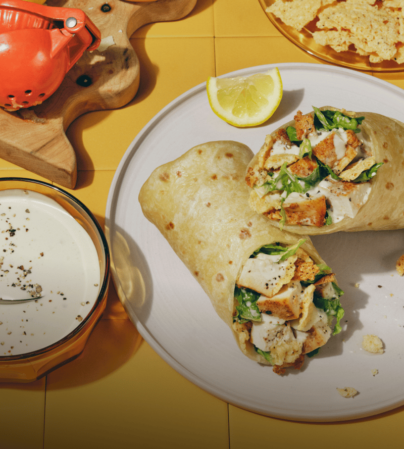 Classic Chicken Caesar wrap on a plate with a yellow tile background