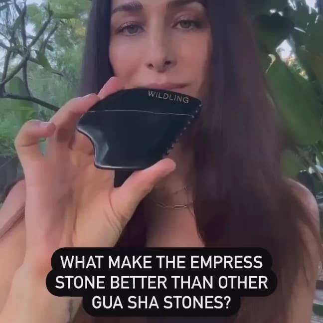 Woman holding the Empress Stone to her cheek outdoors