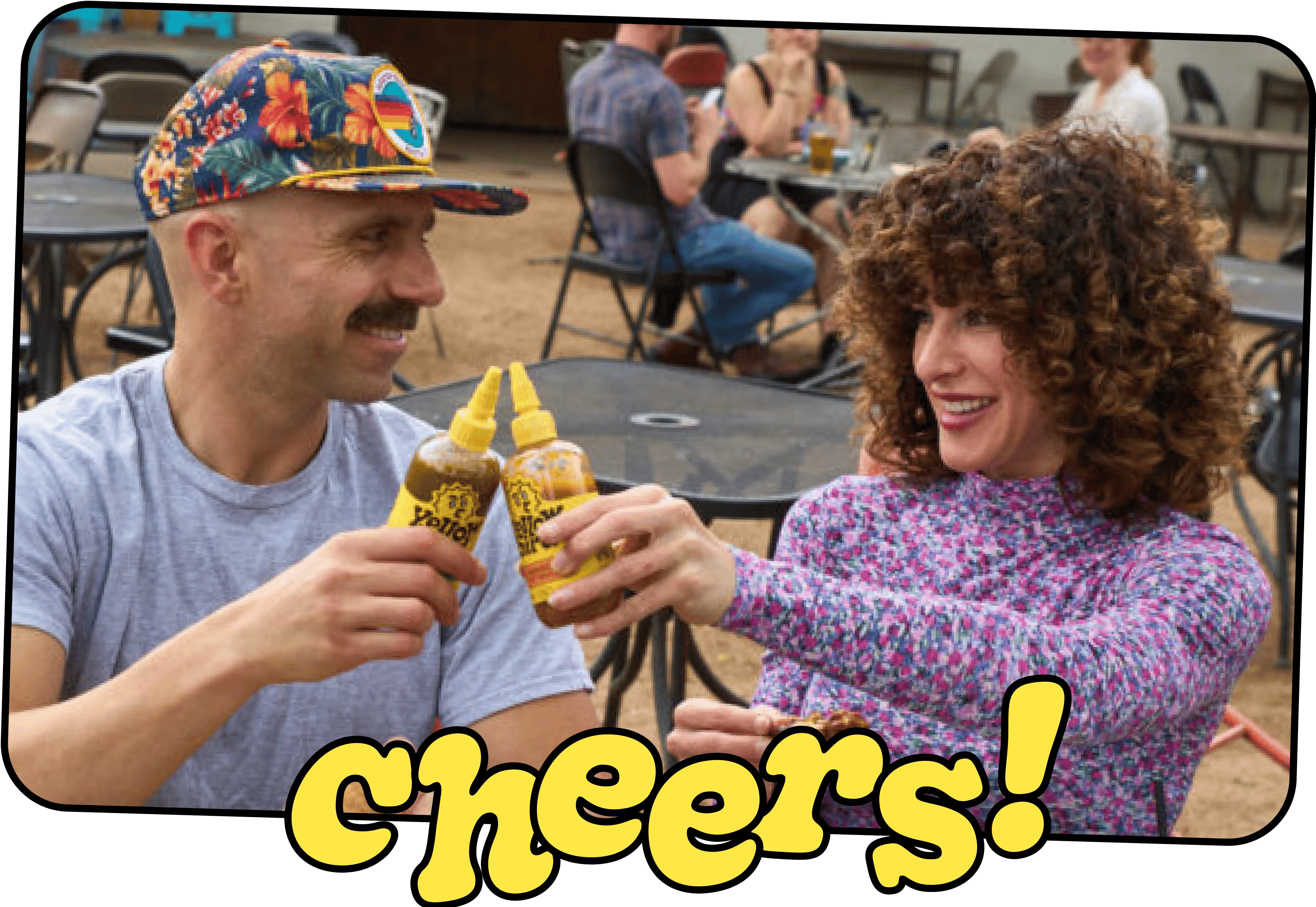 Erin and George, the Yellowbird co-founders, toasting with two bottles of hot sauce