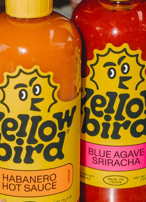 Yellowbird hot sauce being poured on an open pastrami sandwich